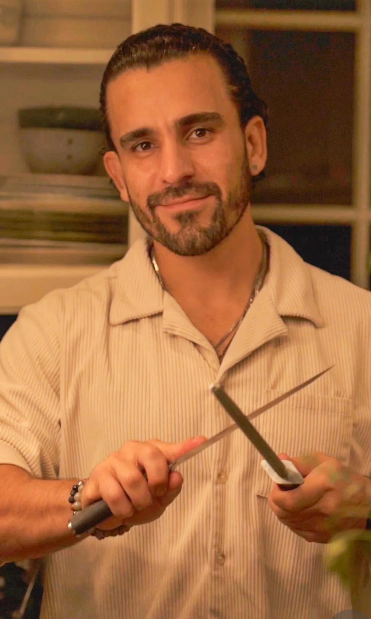 Chef Piaz,  smiling and looking at the camera, sharpening his knofe at a private  event in Los Angeles private chef and founder of PiazMiaz,
