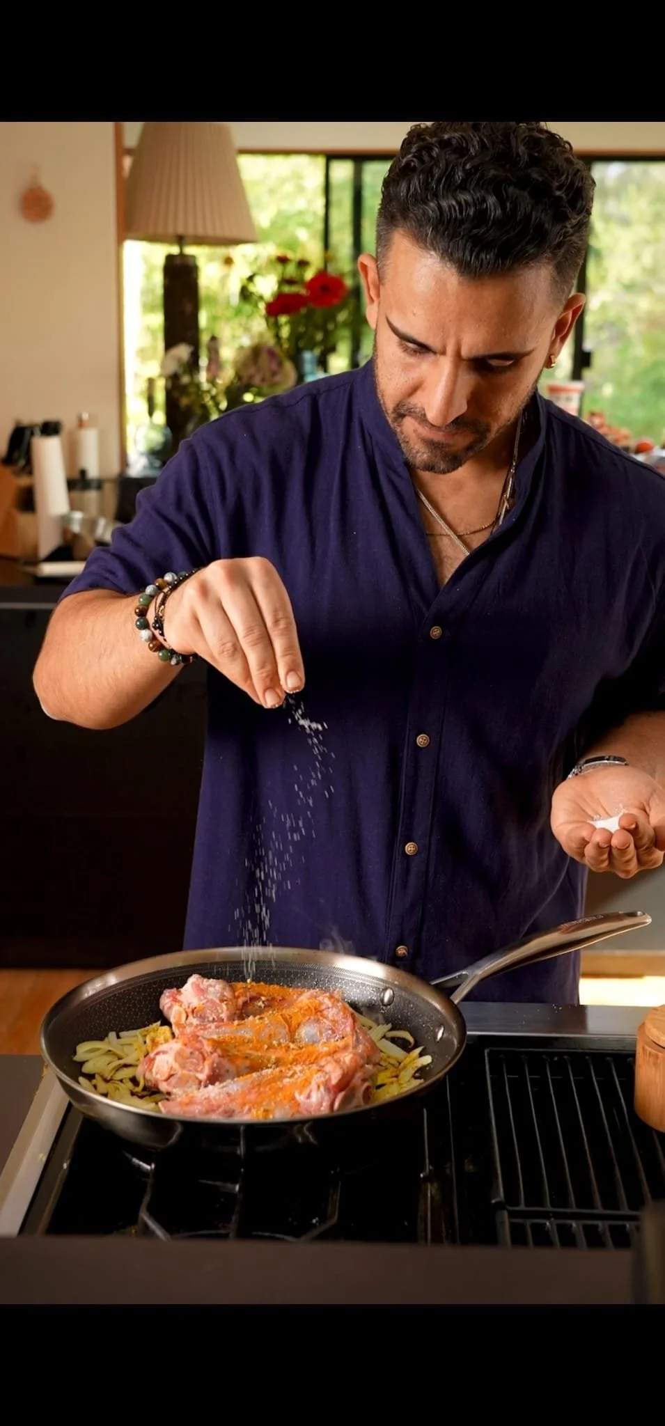 Chef Piaz seasoning chicken and onions in a pan while cooking a private dinner