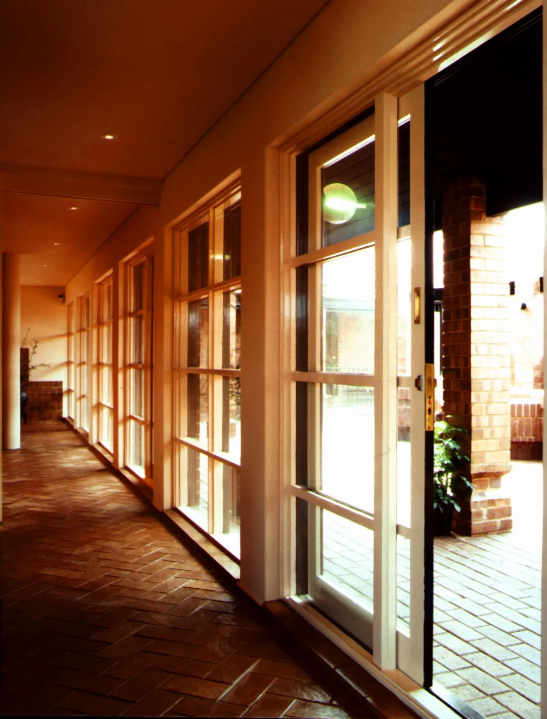 Glazed gallery with French doors opening to a brick-paved courtyard