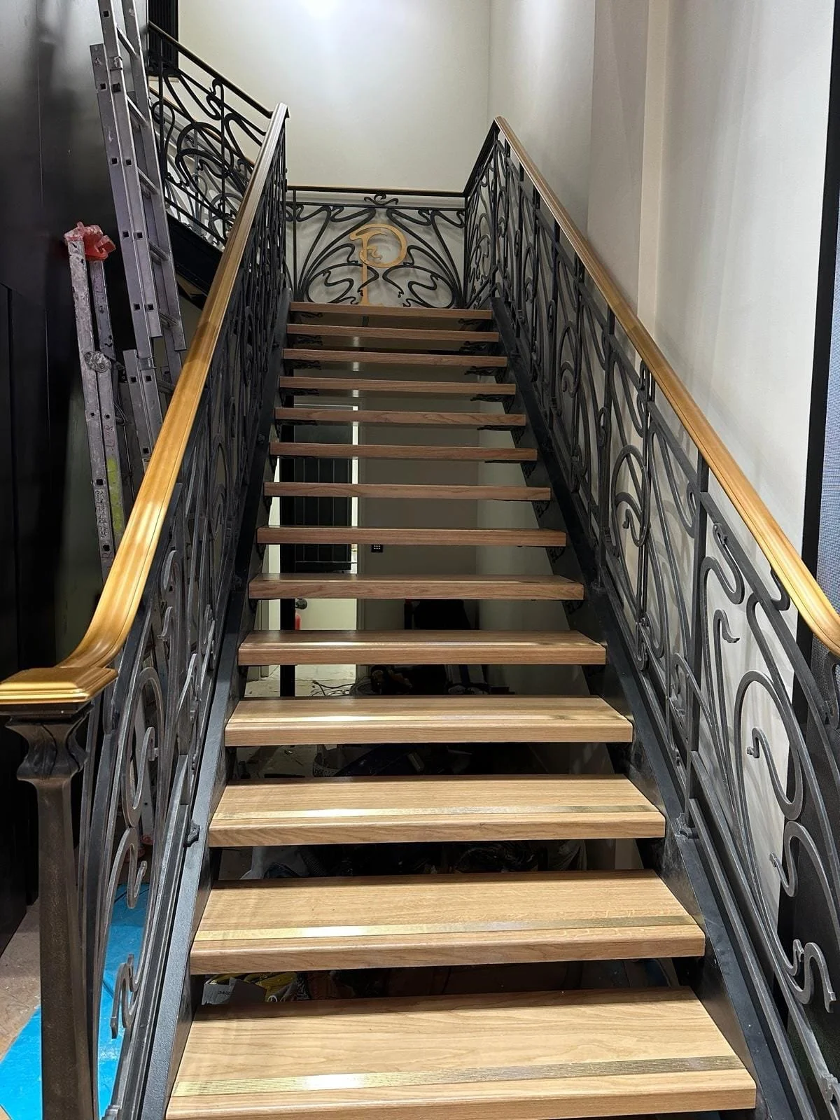Escalier en cours de construction avec des marches en bois et une rampe en métal décorative