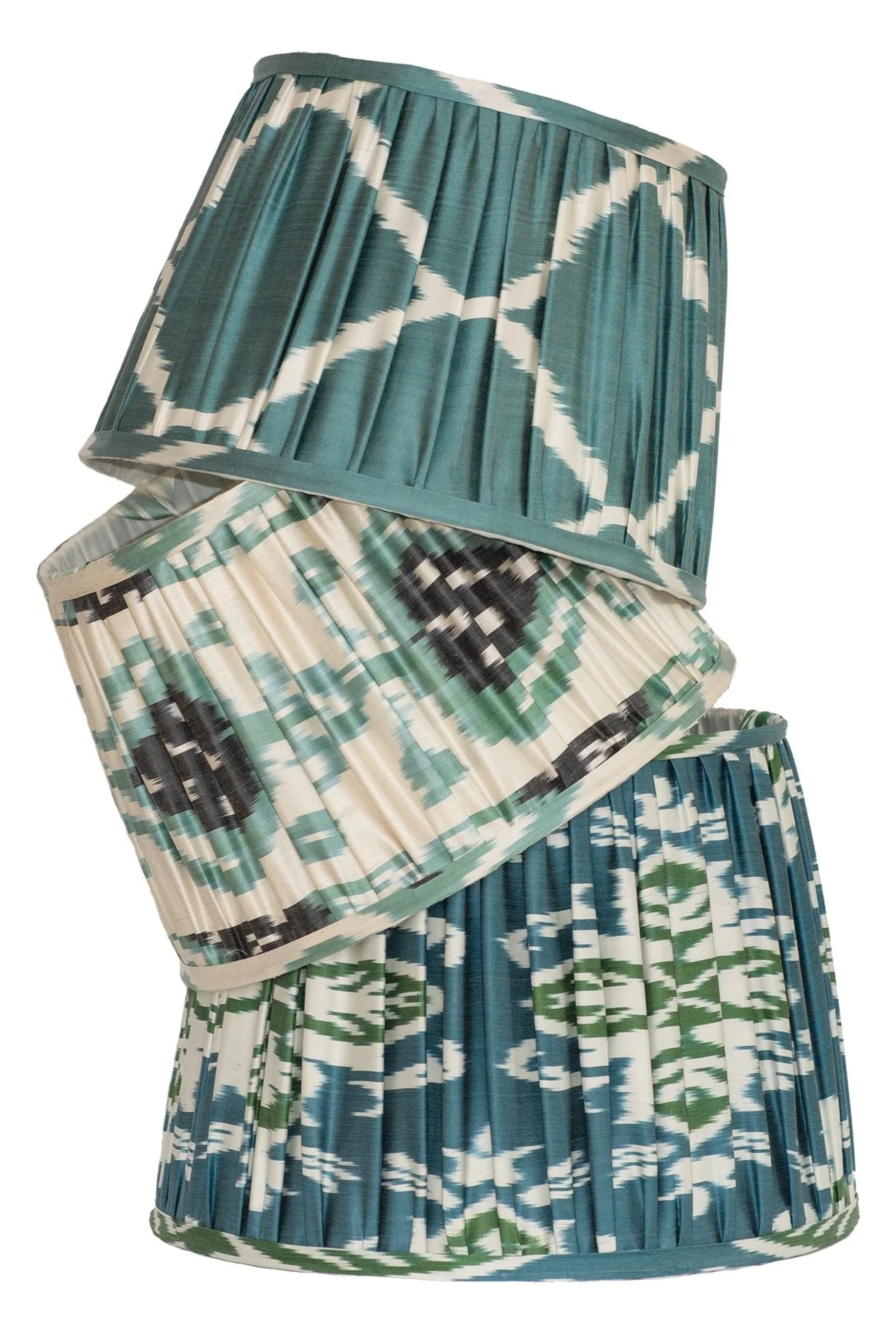 Stack of pleated fabric skirts with geometric patterns in shades of teal, white, black, and green.