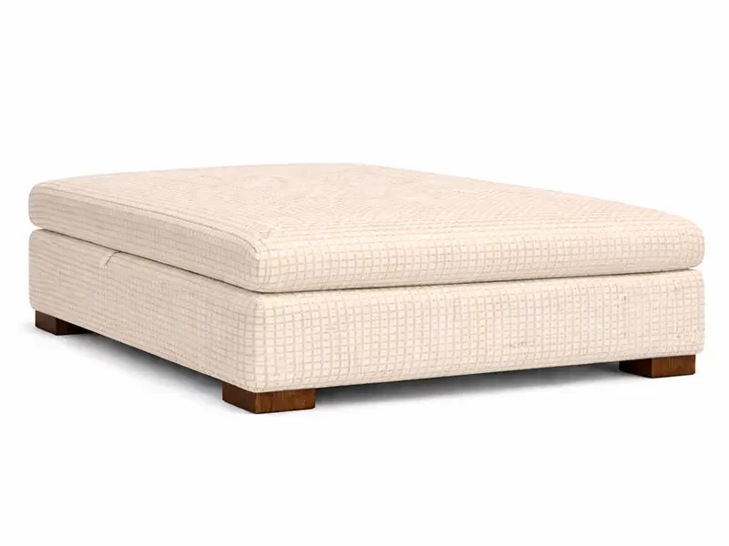 A beige upholstered rectangular ottoman with a cushioned top and wooden block legs.