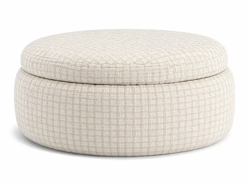 Cream-colored, round upholstered ottoman with a textured fabric surface.