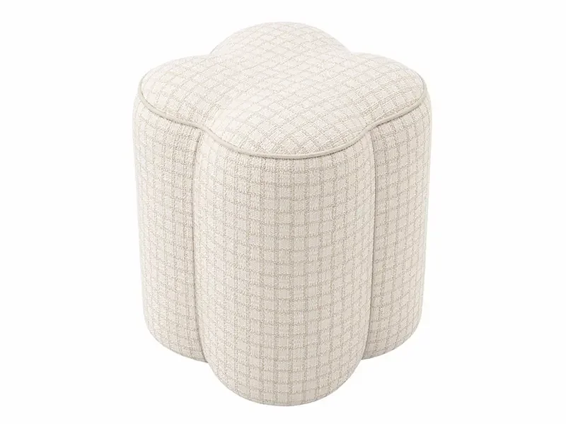 A cream-colored upholstered ottoman with a circular shape and a quilted fabric pattern.