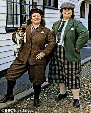 Hermy and Ursy dressed in plaid skirts and blazers standing outside historic houses, with one woman holding a small dog.