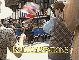 People waiting in line at a service counter, with a person in the foreground holding umbrellas, and a sign that says 'Battle Stations'.