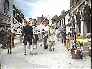 People protesting with banners and signs on a street, with shops and buildings in the background.