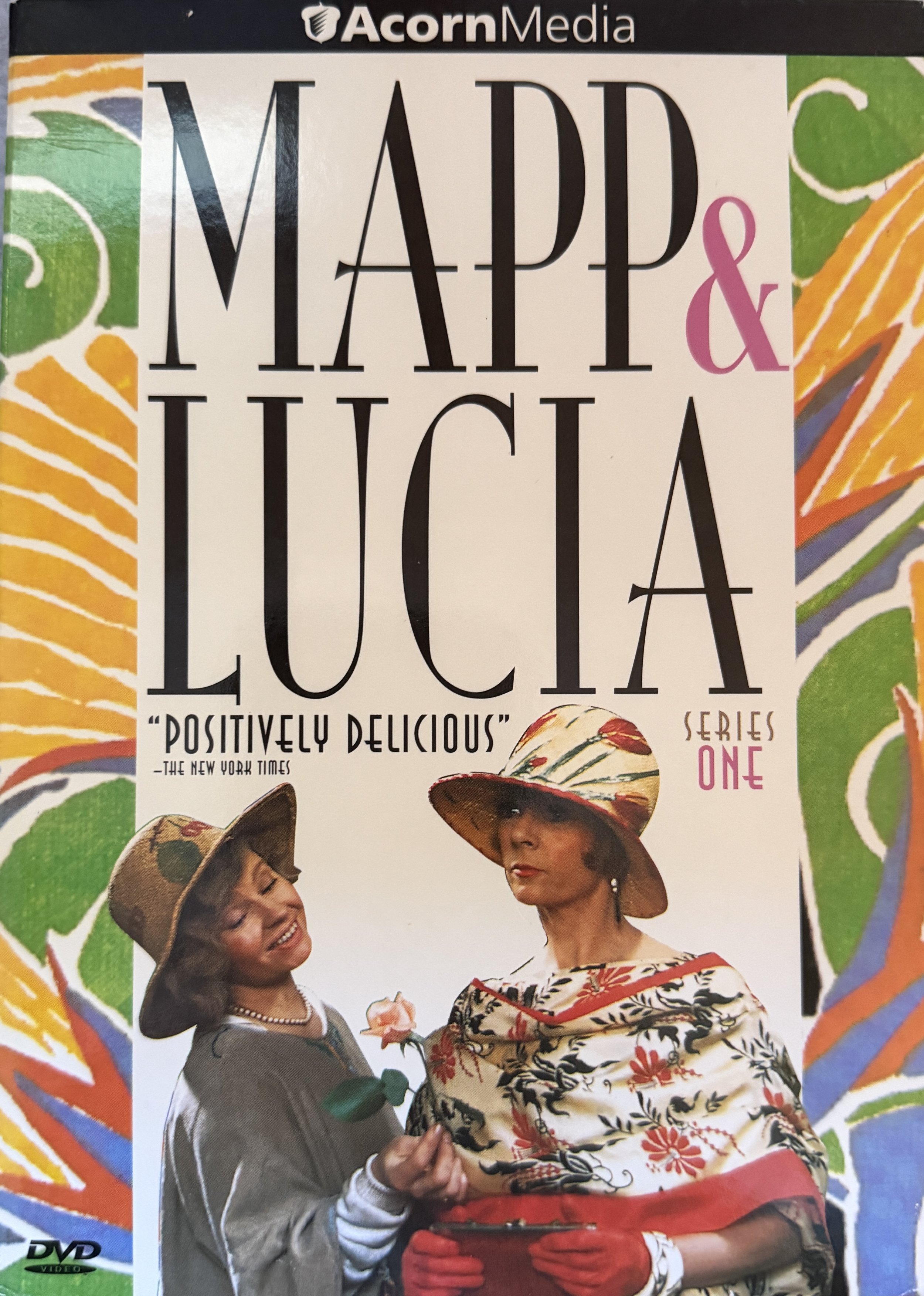 DVD cover titled 'Mapp & Lucía' with colorful abstract border, featuring two women wearing large straw hats and floral clothing, engaging in conversation.