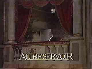 The image shows a theater stage with red curtains and a balcony, with the words 'AU RESERVOIR' displayed.
