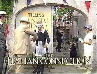 People dressed in historical clothing, with one person adjusting a hat on a woman, standing under an arch with a sign reading 'Tilling the Italian Connection'.
