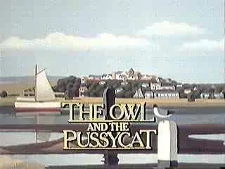 Sign reading 'The Owl and the Pussycat' in front of a coastal town with buildings and trees, under a partly cloudy sky.