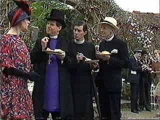 Group of four people outdoors, two women and two men, talking and holding plates of food during a gathering or event.