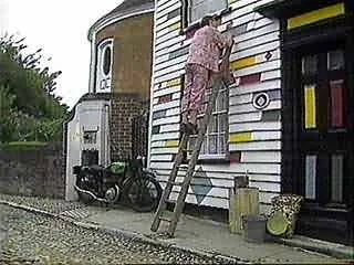 A person painting or working on a mural on the side of a building with black, white, and yellow horizontal stripes.
