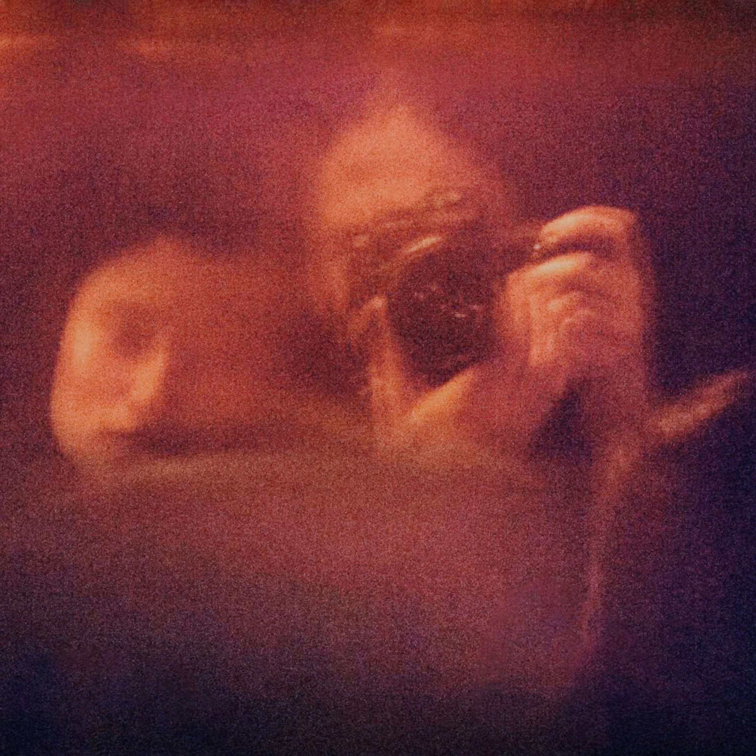 Close-up of a person’s hands clasped together in warm, low light