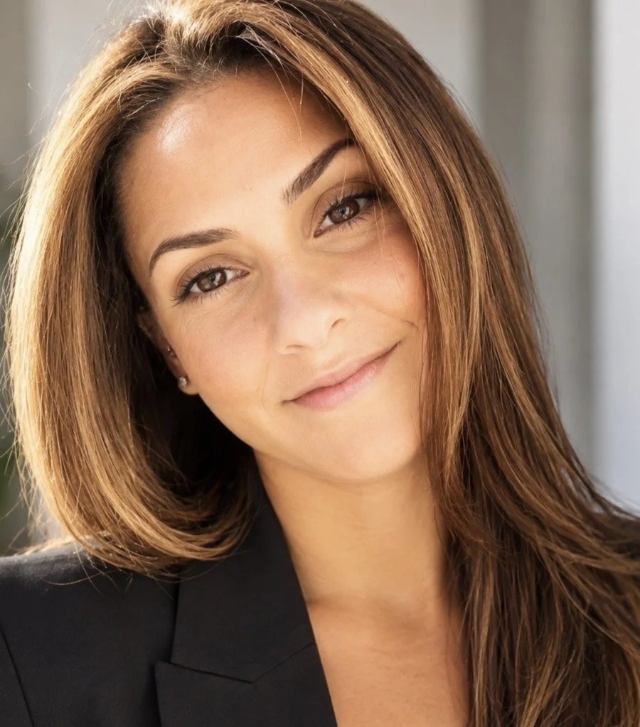 A woman with light brown hair and brown eyes smiling at the camera.