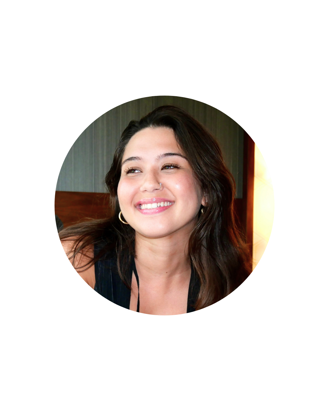 Smiling woman with long dark hair, hoop earrings, and a nose ring