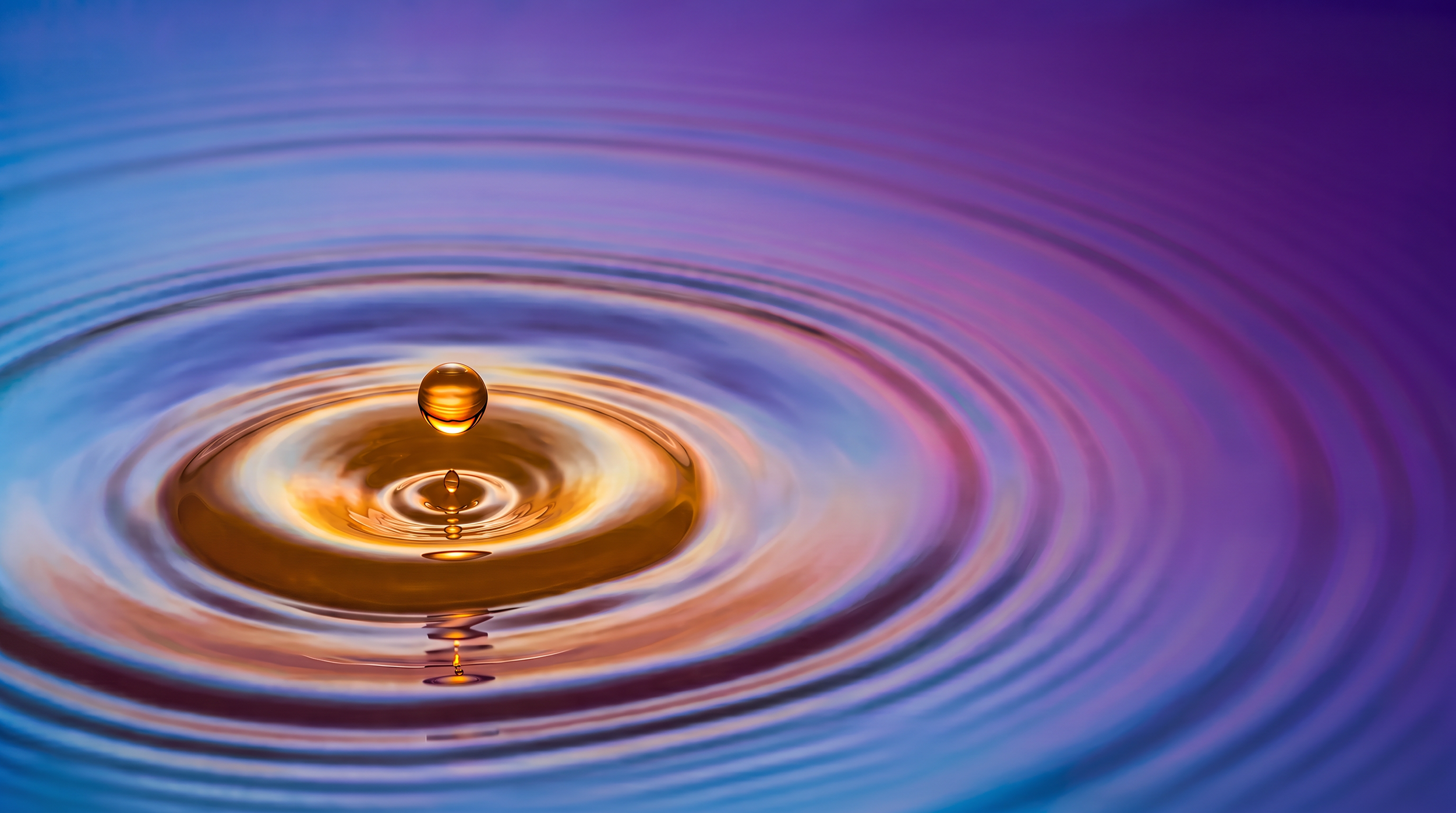 Drop of water splashing with ripples in a lake at sunset