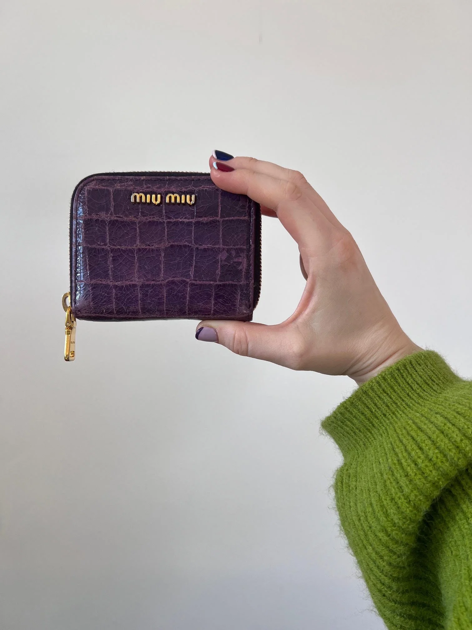 plum leather miumiu wallet with croc texture, gold logo and gold zipper detail.
