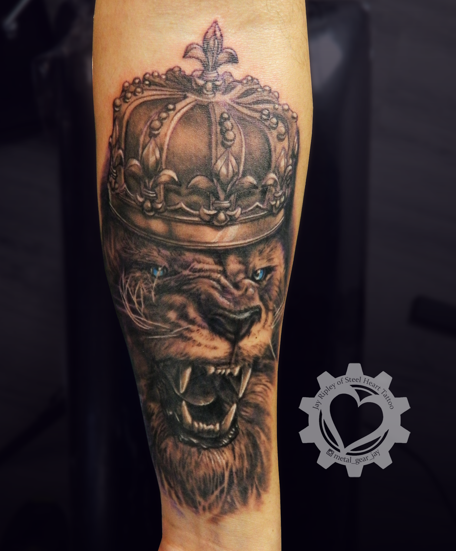 Detailed black-and-gray tattoo of a snarling tiger wearing an ornate crown on a forearm