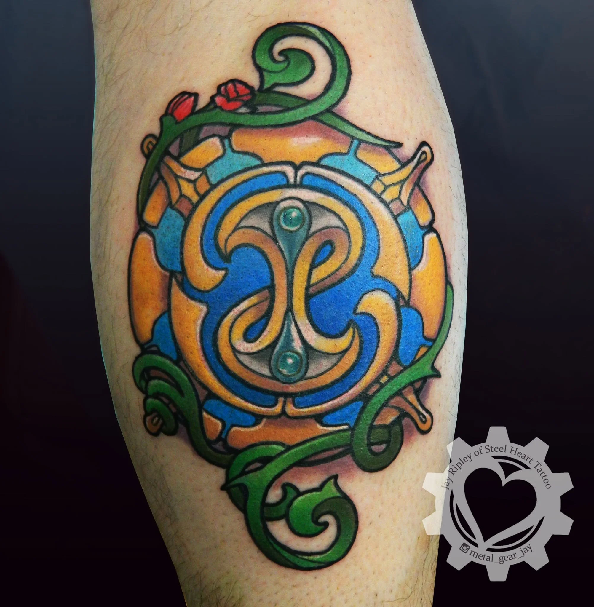 Colorful Celtic-style tattoo featuring a central blue, orange, and green circular knot design with spiraling vines and red floral accents.