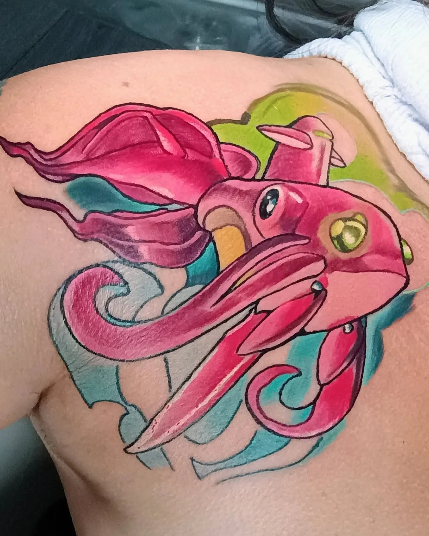 Colorful tattoo of a pink and teal fantasy dragon with large wings and a curled tail.