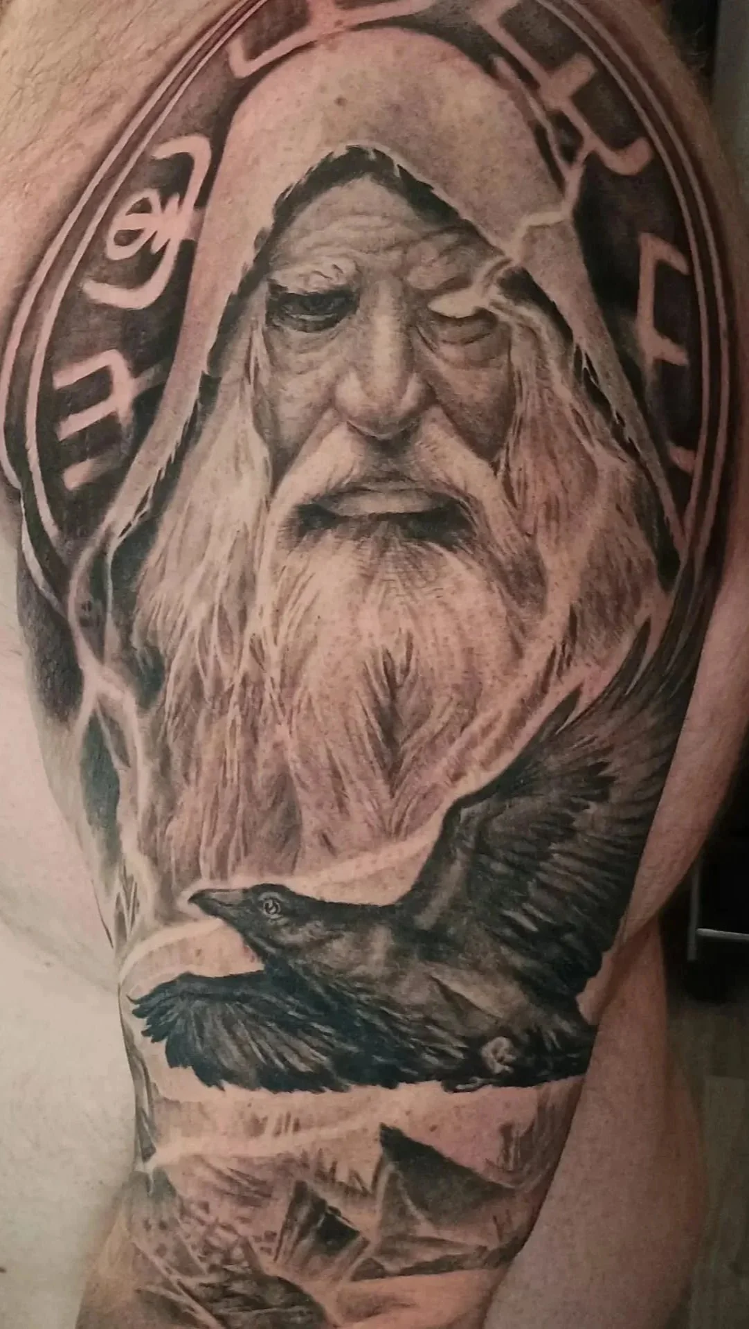 Detailed tattoo of an elderly bearded man with a crow perched on his arm