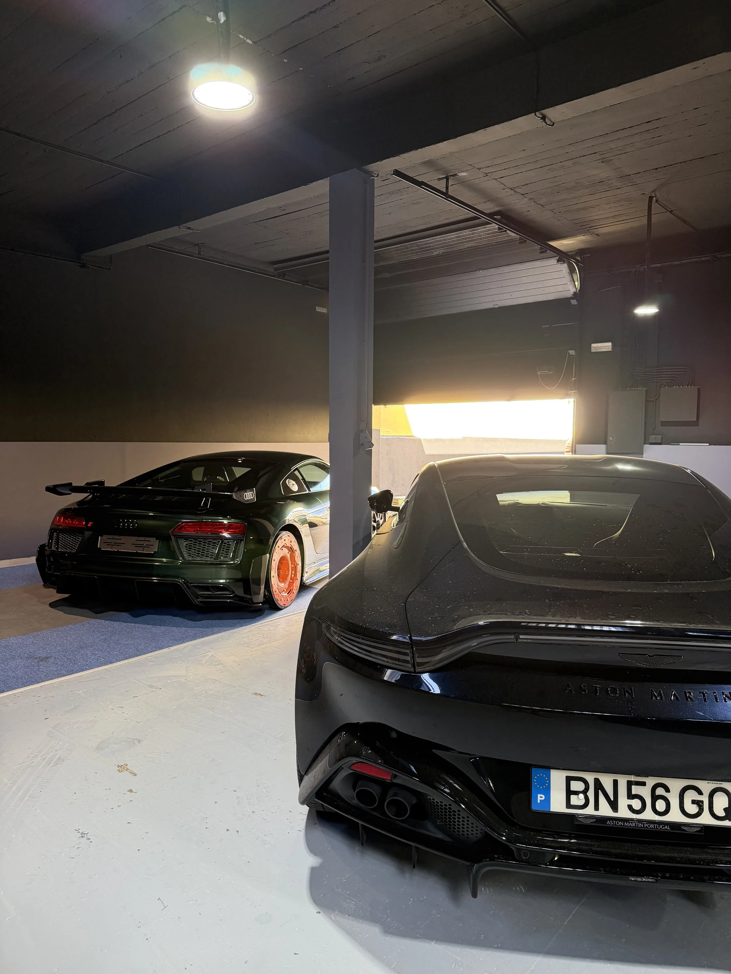 Inside the Bainbridge & Co. Discreet High-End Car Storage garage, black sports and Super cars parked side by side. Luxury Atmosphere with nice lighting, epoxy floor.