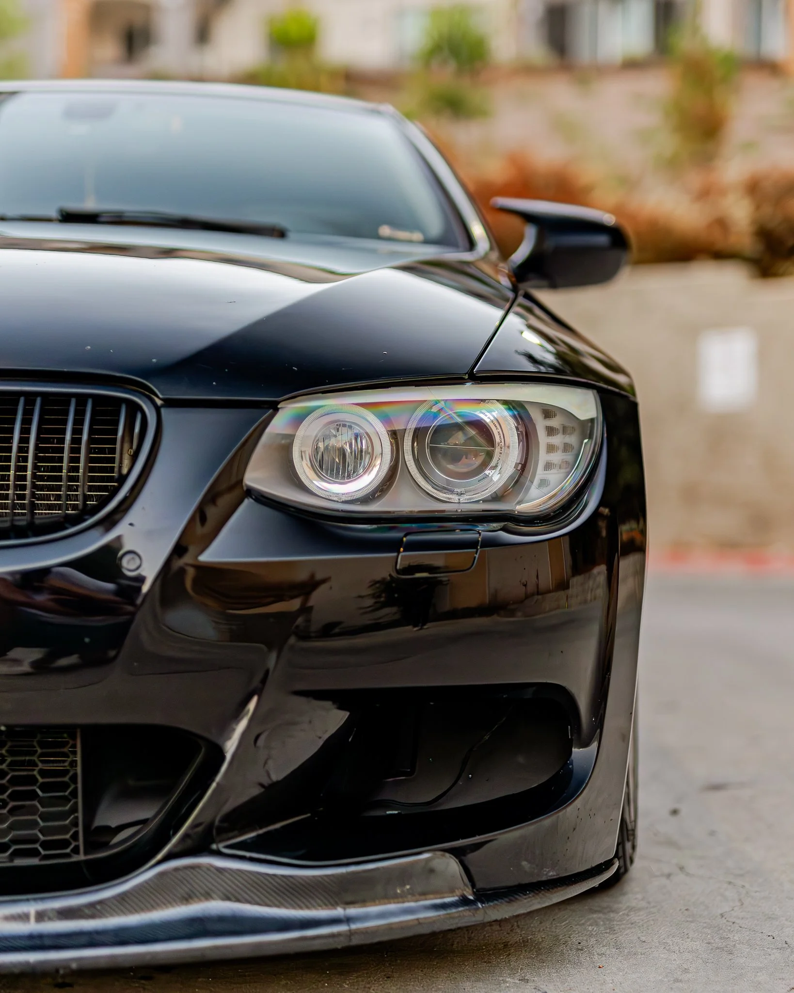 Close-up of the front left side of a black luxury car with modern headlight design and chrome detailing.