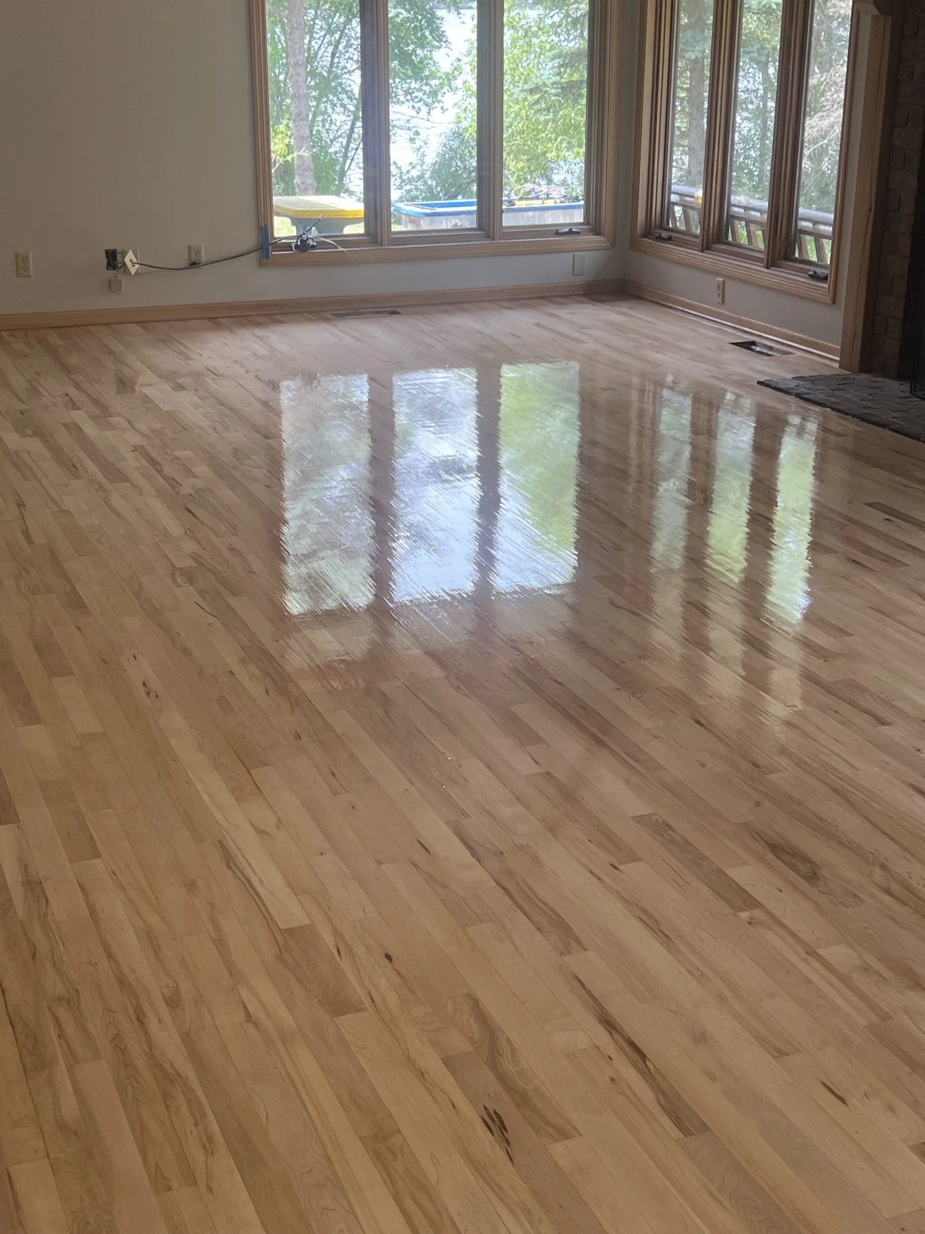 Newly installed hardwood floor in a room with large windows