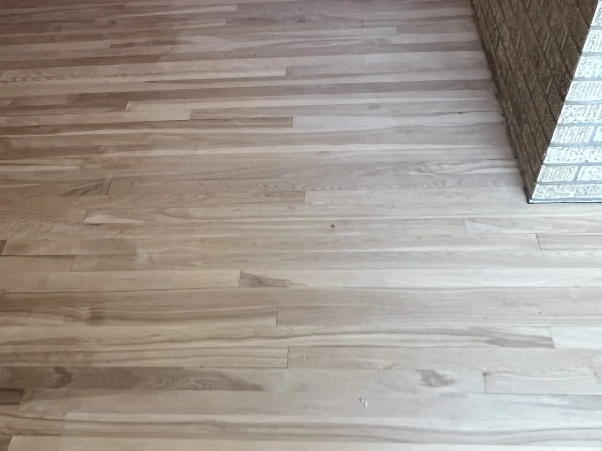 Wooden hardwood floor with a brick wall corner on the right side.