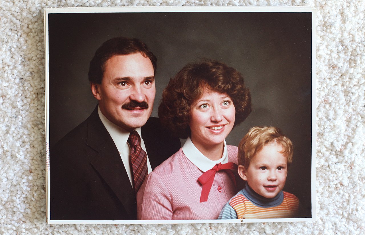 Vintage family portrait of a mustached man, smiling woman, and young boy in a striped sweater