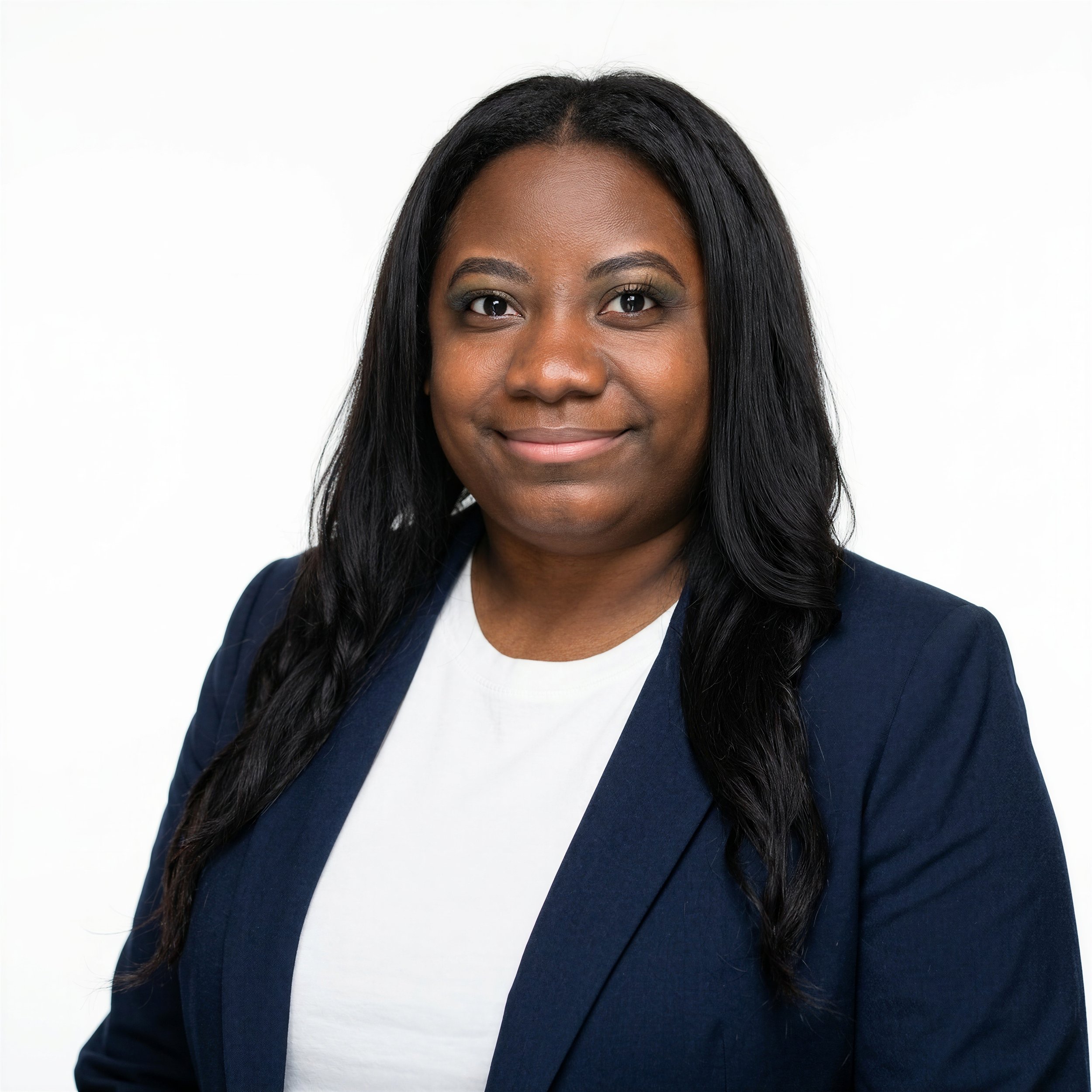 Close-up portrait of a smiling Black woman with straight black hair, wearing a navy blue blazer and white top, against a plain white background.
