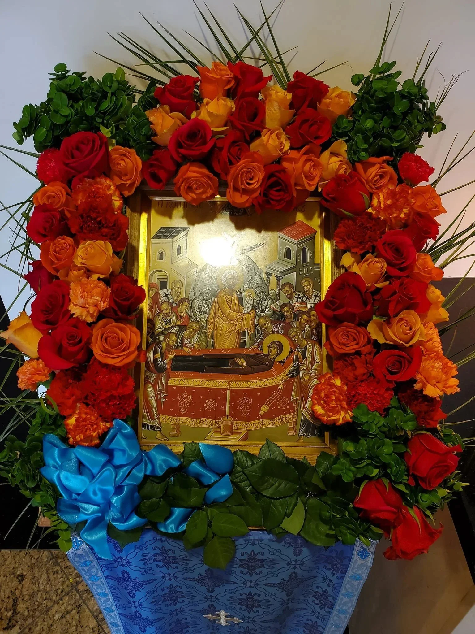 Icon on a stand framed with red and orange roses