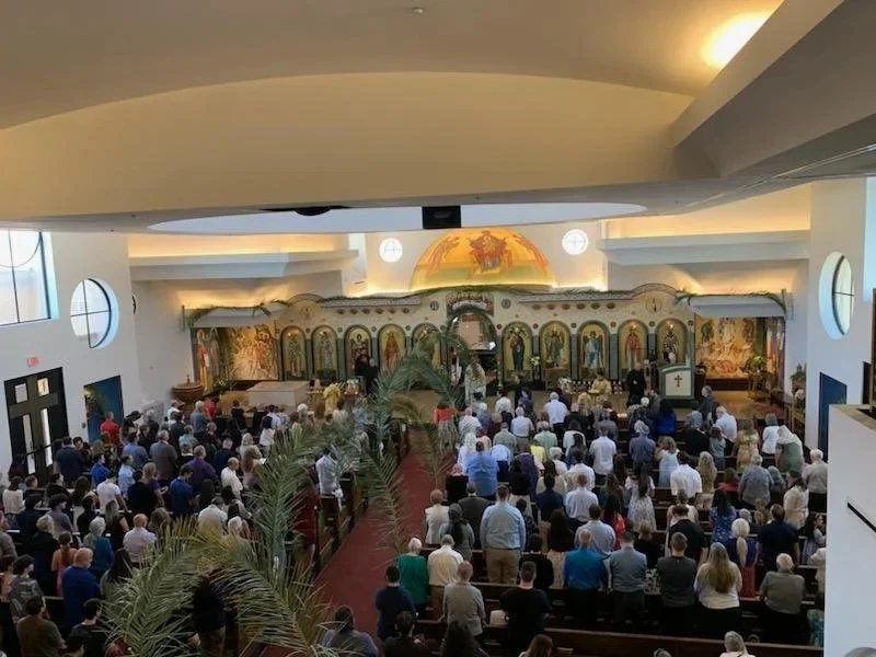 Full church on Palm Sunday with palms along the aisle