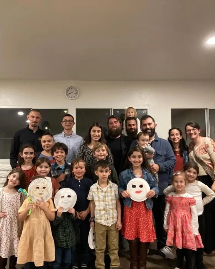 Group photo of families, with children holding paper masks
