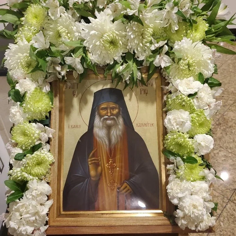 Icon of a monastic saint framed with white and green flowers