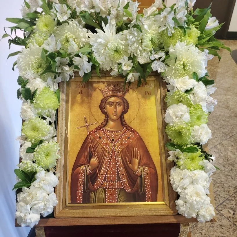 Icon of a female saint framed with white and green flowers