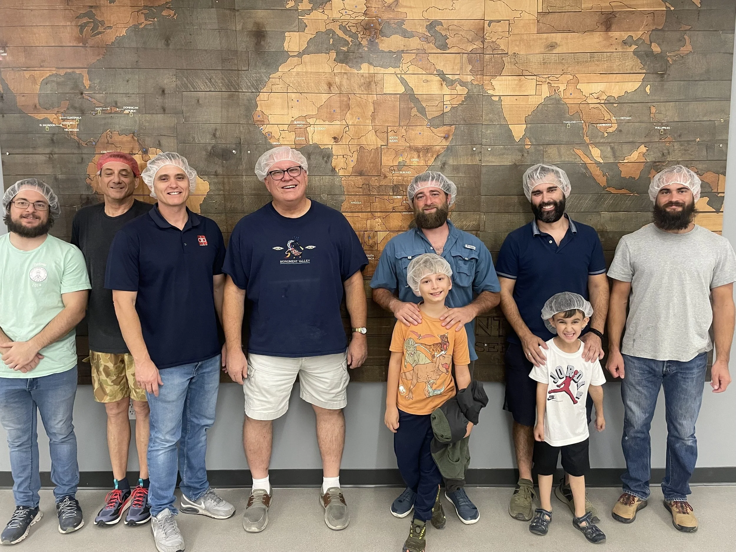 Men and boys posing in front of a world map mural