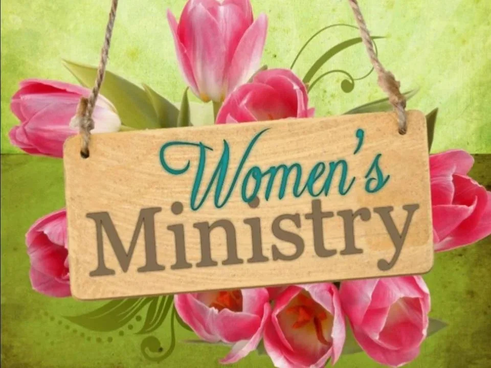 Wooden sign reading 'Women's Ministry' surrounded by pink tulips
