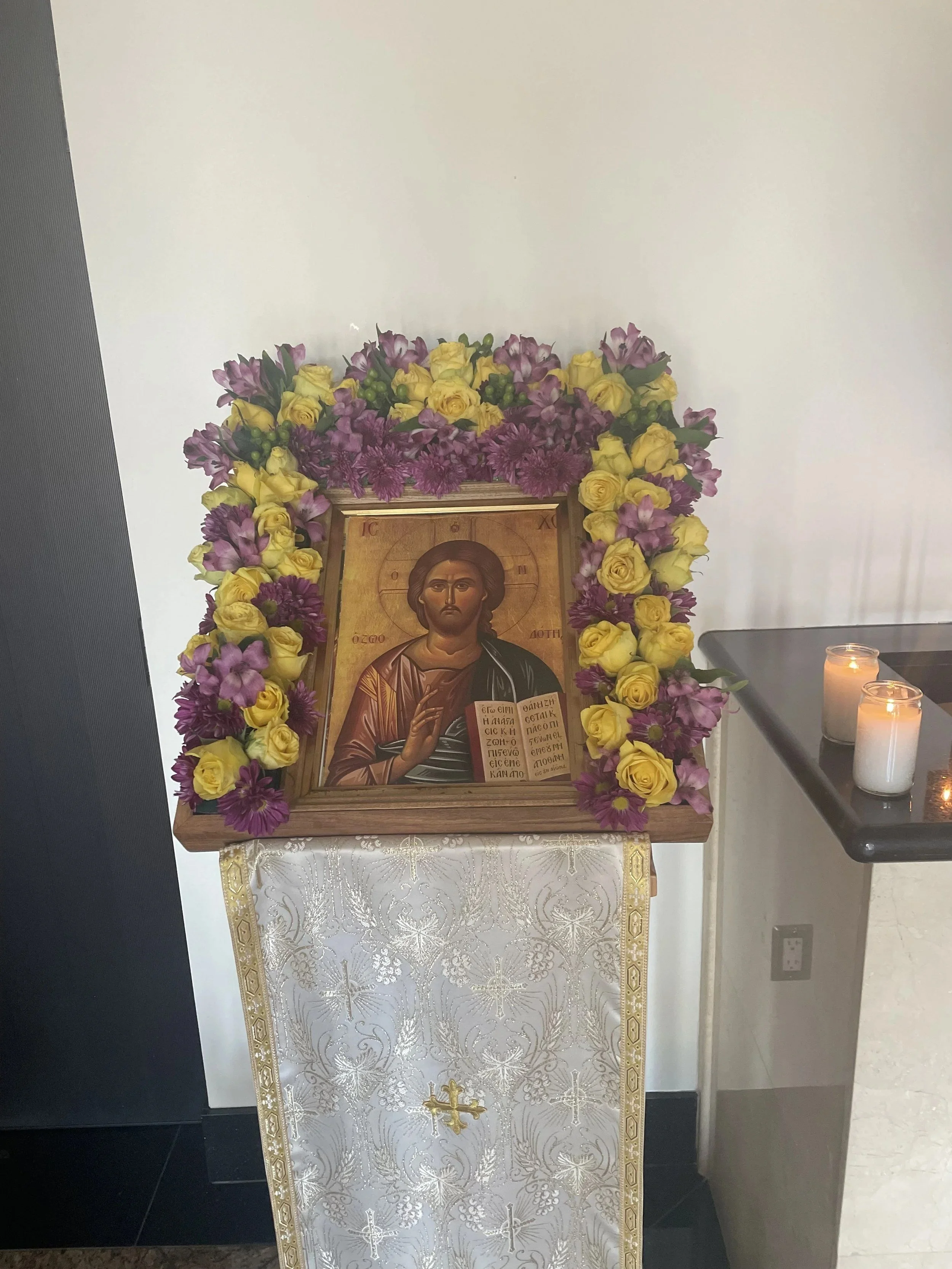 Icon of Christ framed with purple and yellow flowers