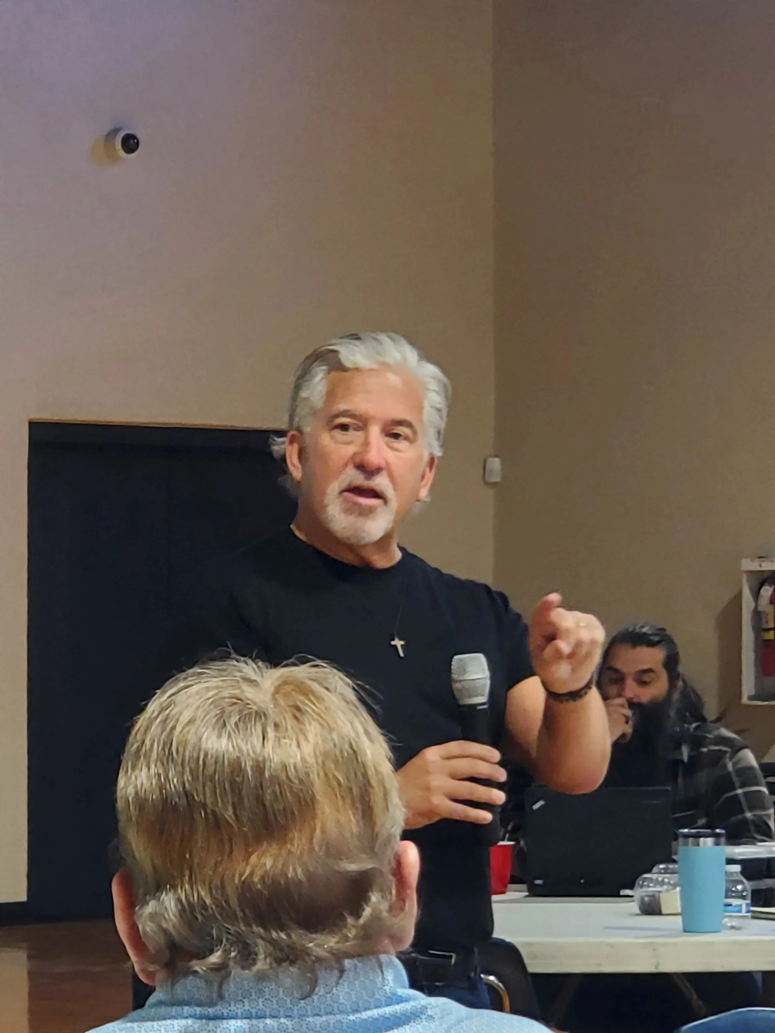 A speaker with a microphone addresses the Men's Ministry