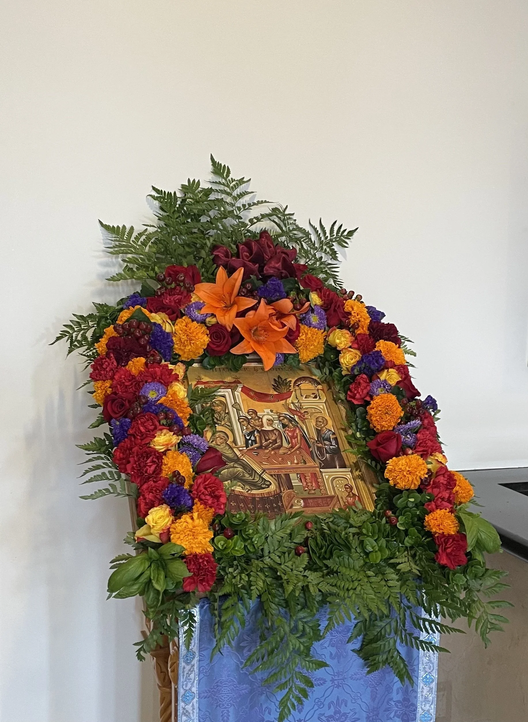 Feast icon framed with orange lilies, roses and ferns