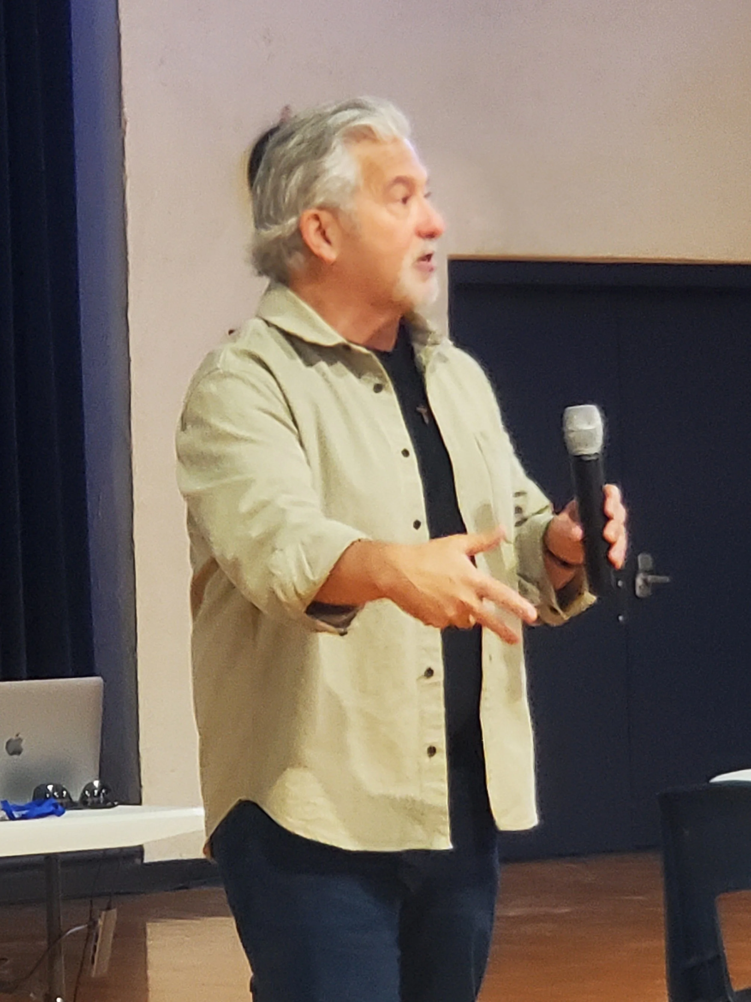 A speaker with a microphone addresses the Men's Ministry