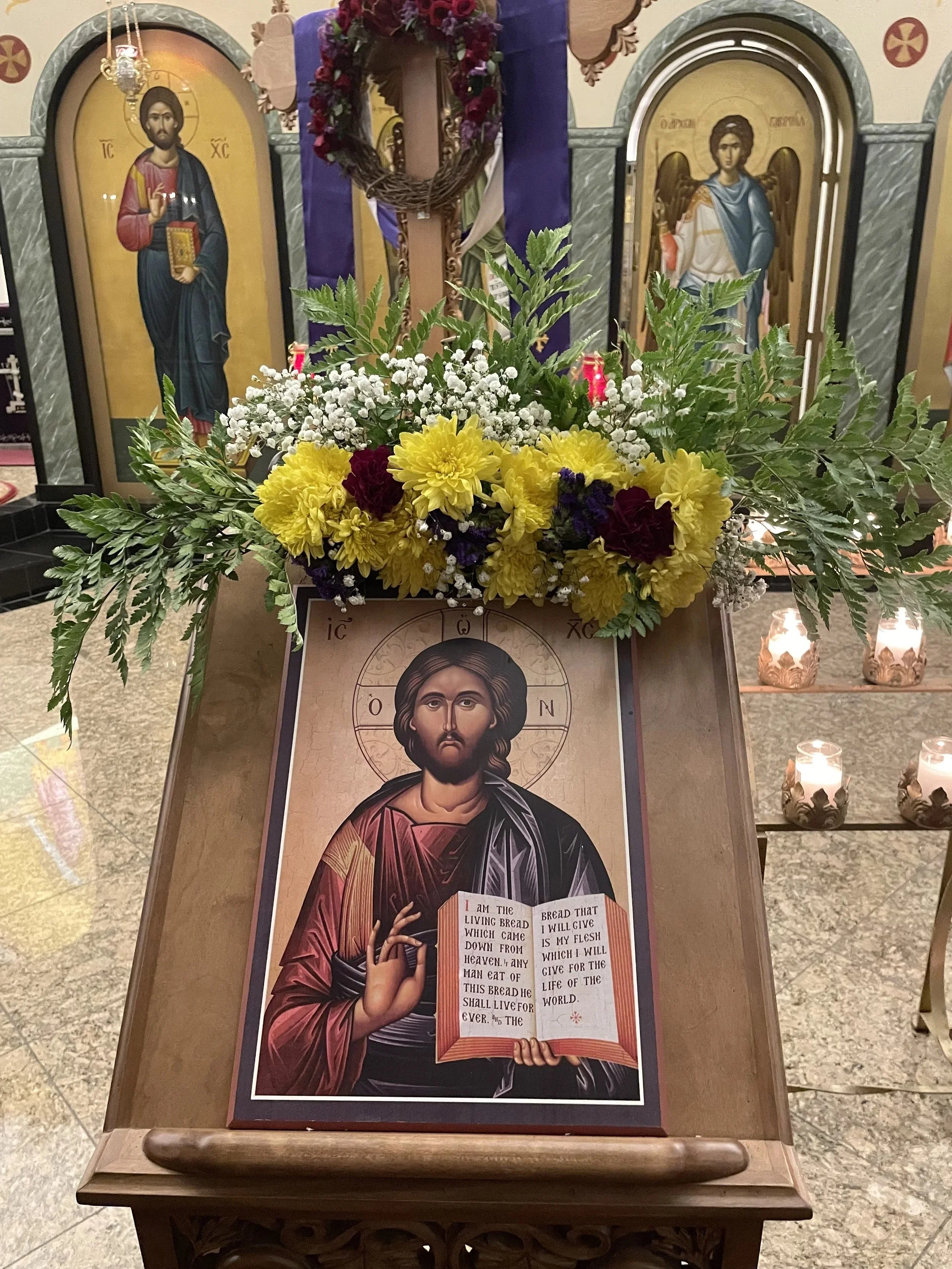 Icon of Christ topped with yellow and white flowers