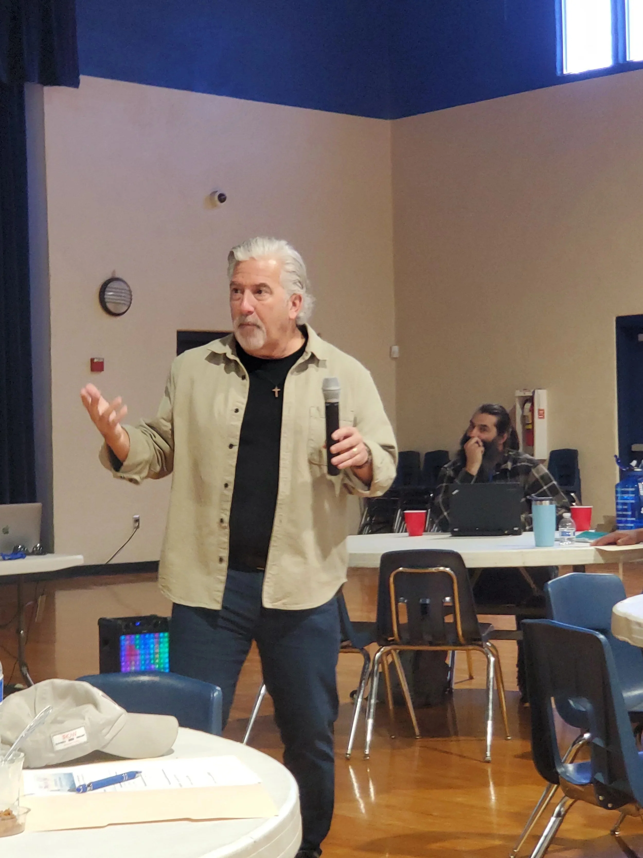 A speaker with a microphone addresses the Men's Ministry
