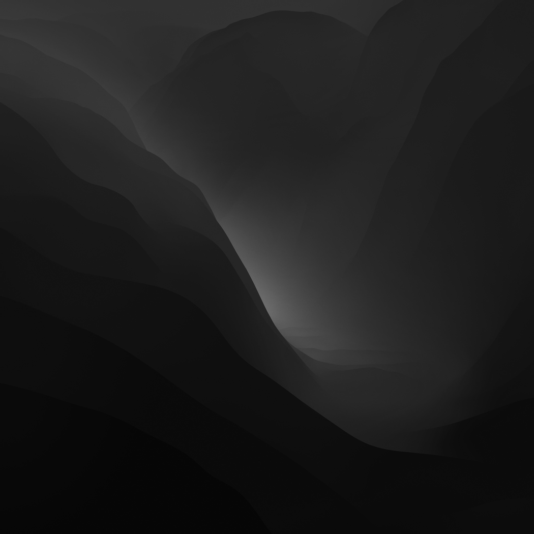 A grayscale image of a mountain landscape with layered mountain ridges and a misty valley in the distance.