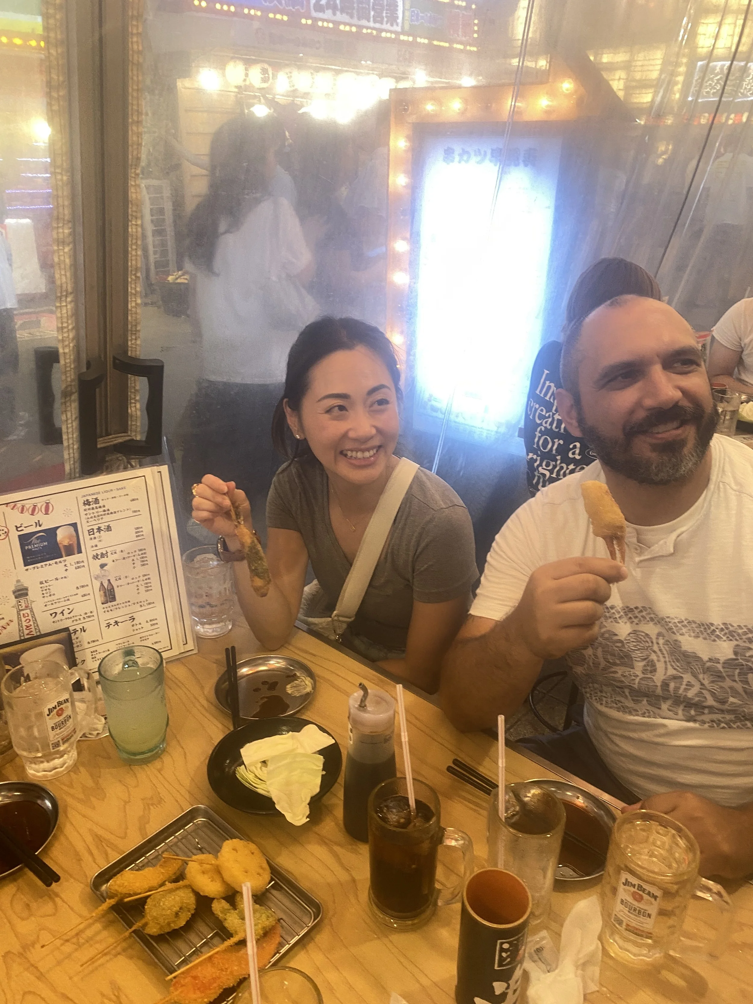 Guests eating freshly made kushikatsu (skewered meat). Have fun on the Osaka Food Tour.