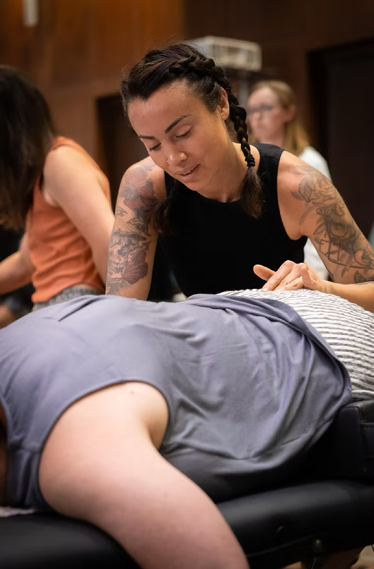 Kelsi Winter offering a gentle, hands-on Spinal Flow session to a client lying face down on a treatment table in Langley, BC