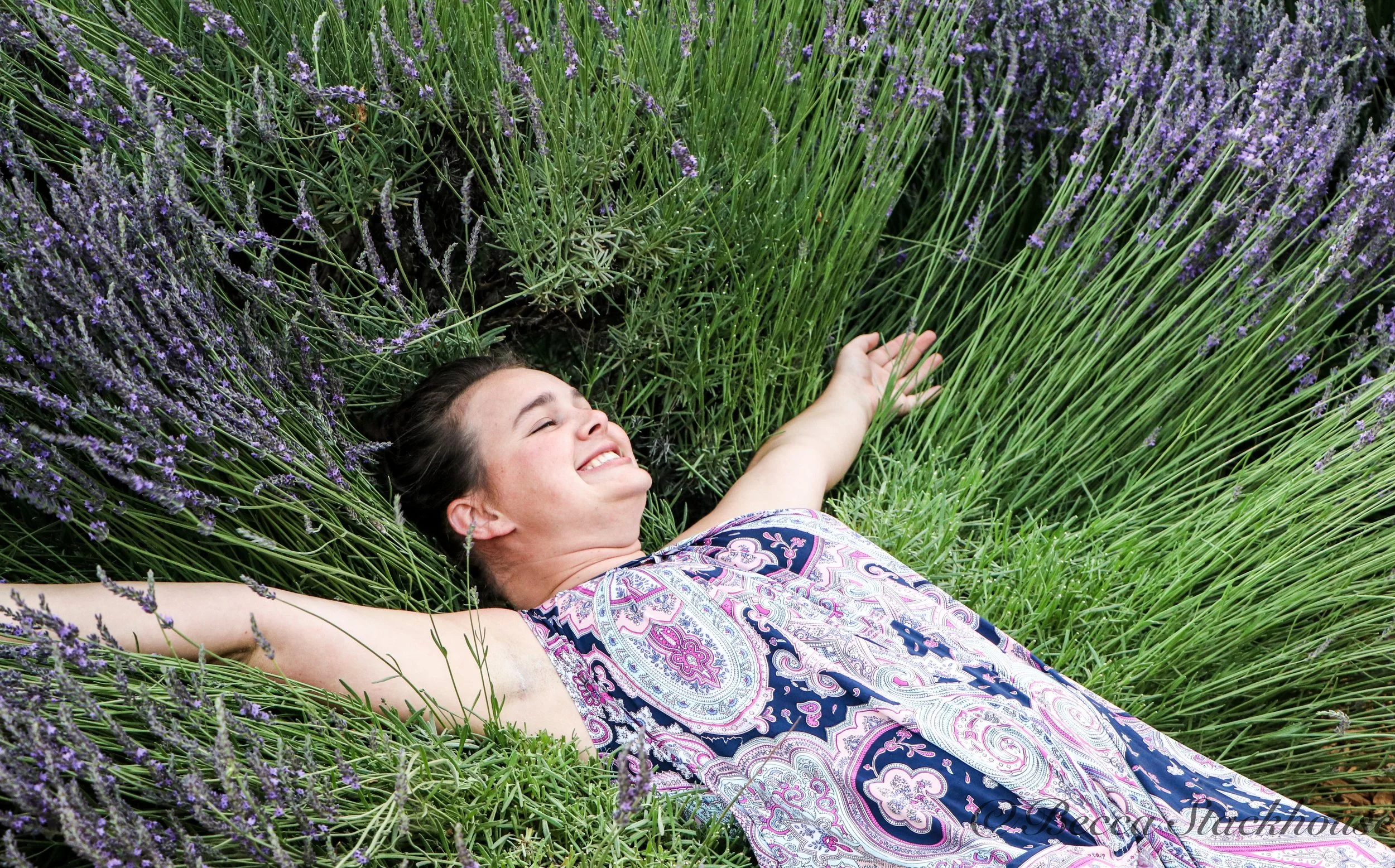 Smiling woman lying among blooming purple lavender plants