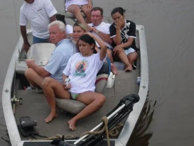 A group of people sitting in a boat on a body of water, with some looking around and one person resting.